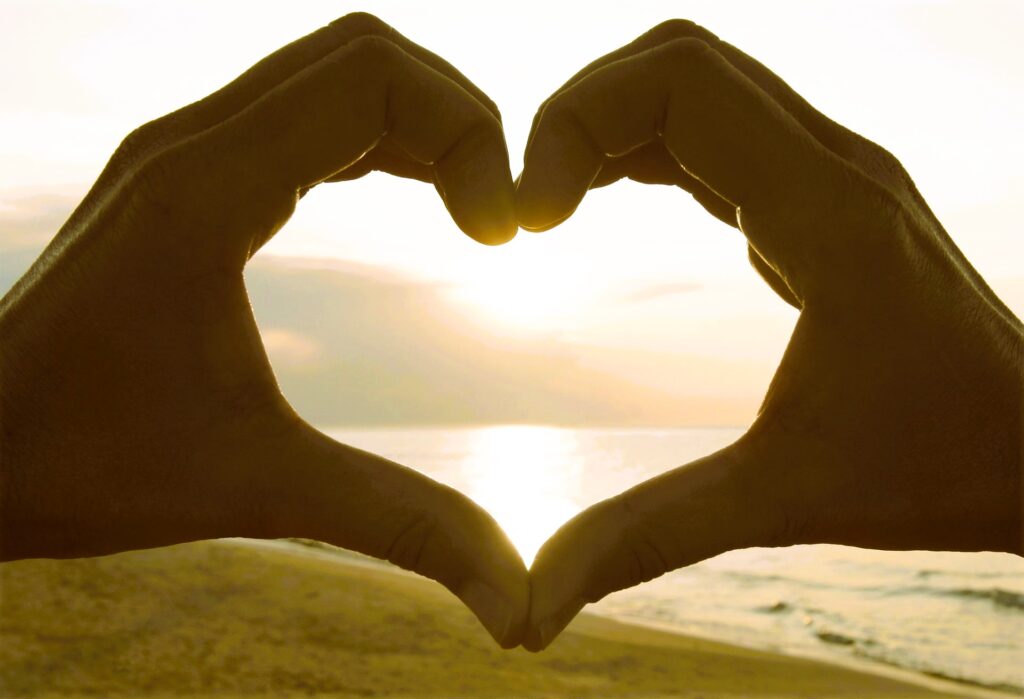 Hands Make A Heart; Down by the seaside a heart shape made with hands frame the setting sun